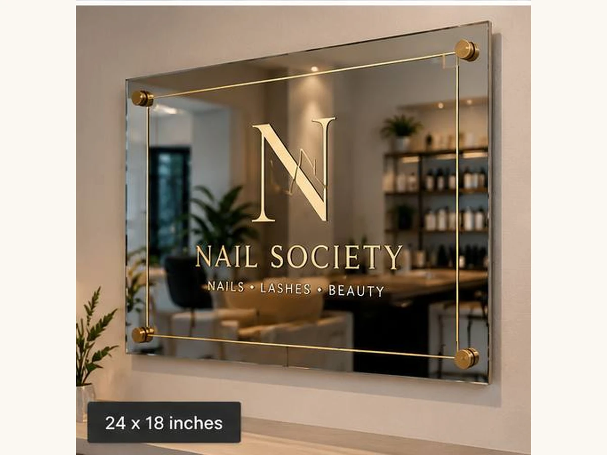 Illustrative Nail Society mirror logo sign with gold-tone printing and four corner mounts